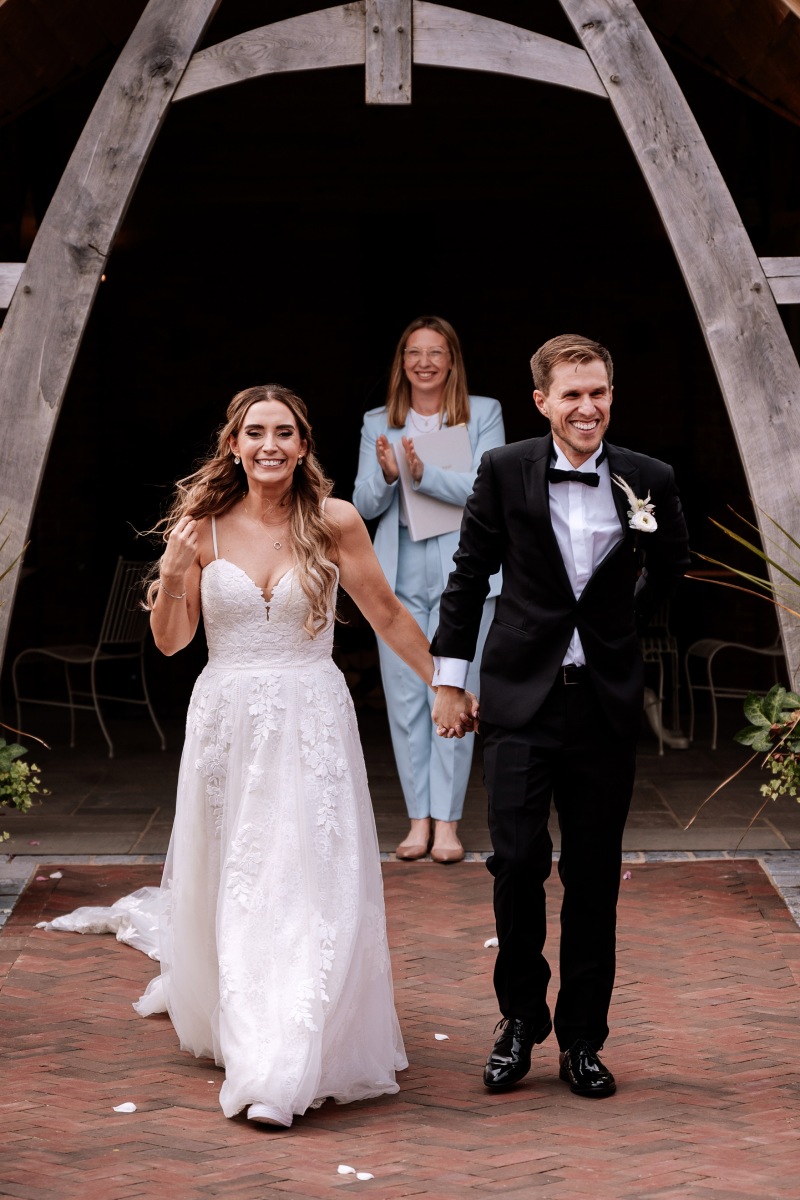 Just married couple Hannah & Lewis walking down the aisle with Olivia clapping