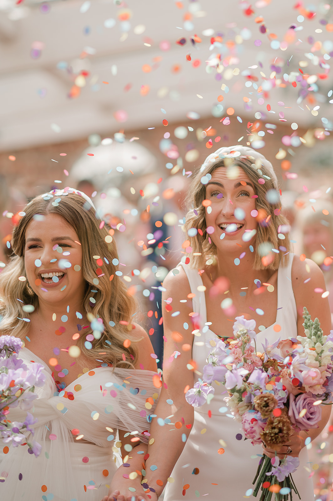 Radiant moment: Just-married brides, guided by celebrant Olivia, walk down the aisle, confetti showering their beaming faces with joy.